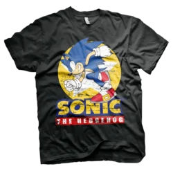 Sort T-shirt med en dynamisk illustration af Sonic, der løber med sit klassiske blå look, røde sko og hvide handsker. Baggrunden har en gul cirkel med en let slidt effekt, og teksten "Sonic The Hedgehog" står i gule og røde bogstaver.
