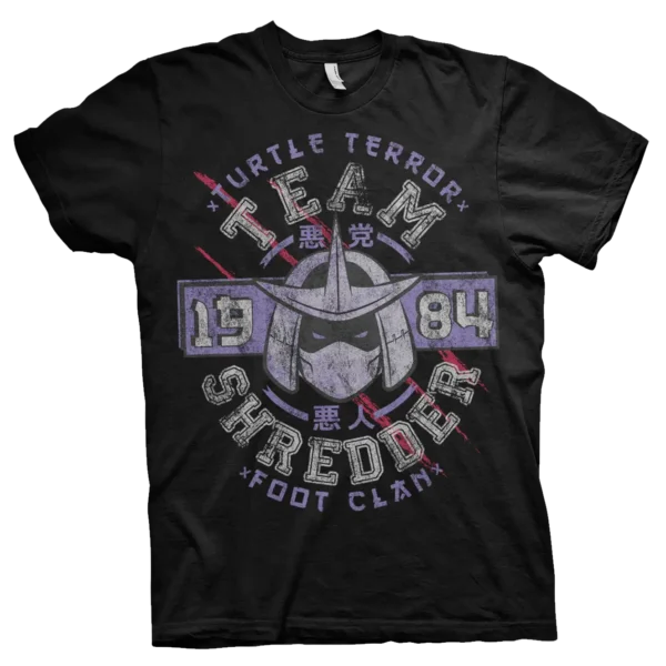 Sort T-shirt med et råt, slidt design af Shredder fra Teenage Mutant Ninja Turtles. Teksten "Team Shredder" og "Foot Clan" er omgivet af japanske tegn, årstallet 1984 og røde klør-ridser, der giver et kampklart udtryk.